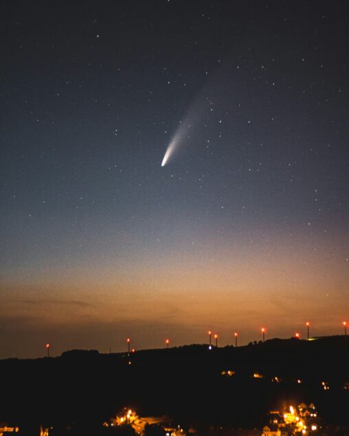 Comet falling at sunset over red lights over a landscape